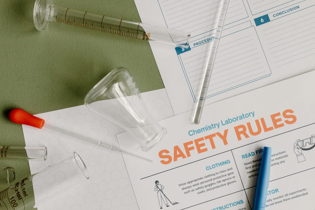 Flatlay of chemistry lab safety rules and various glassware on a table.